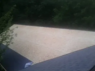 New OSB roof sheathing installed beside an existing shingle roof in Carpenter