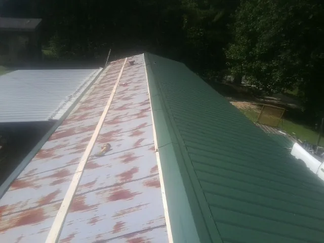 Old rusted panels beside newly installed green metal roofing — Wind Damage Roof Repair by Roofing Brothers in Carpenter